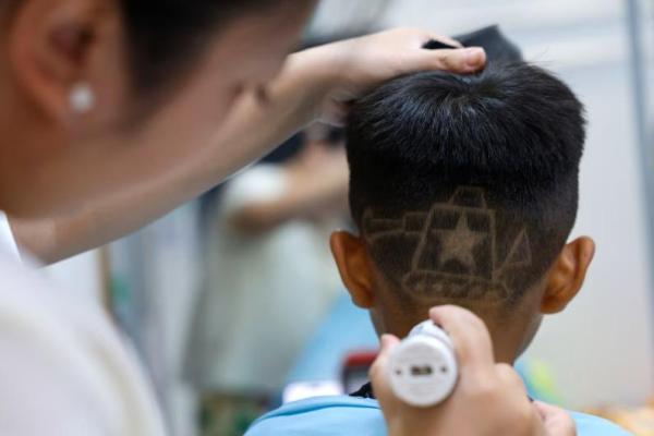 Pemilik salon rambut Wang Xueru memberikan potongan rambut berdesain tank kepada seorang anak di tokonya di Beijing, Tiongkok, 28 Agustus 2025. REUTERS 