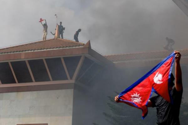 Demonstran mengibarkan bendera saat asap mengepul di kompleks Parlemen, di Kathmandu, Nepal, 9 September 2025. REUTERS 