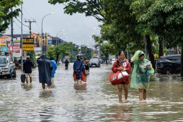 Orang-orang yang membawa barang-barang mereka mengarungi jalan yang tergenang banjir di Legian, Badung, Bali, Indonesia, 10 September 2025. REUTERS 