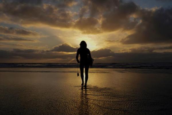Seorang peselancar wanita berjalan di atas ombak di Pantai Negara Bagian Cardiff di Encinitas, California, AS, 17 Oktober 2019. REUTERS 