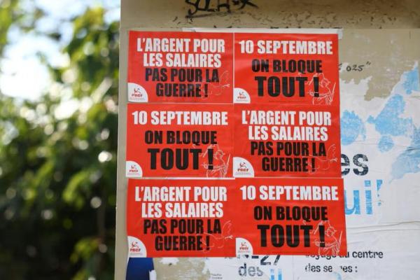 Poster bertuliskan slogan terlihat di dinding di Paris, sehari sebelum gerakan protes akar rumput yang disebut Bloquons Tout, menyerukan aksi mogok nasional sepanjang hari, Prancis, 9 September 2025. REUTERS 