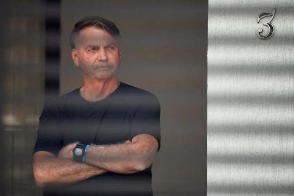 Mantan Presiden Brasil Jair Bolsonaro berdiri di rumahnya saat menjalani tahanan rumah, di Brasília, Brasil, 14 Agustus 2025. REUTERS 