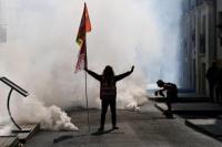Seorang pengunjuk rasa yang memegang bendera serikat buruh CGT berdiri di tengah gas air mata saat unjuk rasa Bloquons Tout atau Mari Blokir Semuanya, Prancis, 18 September 2025. REUTERS
