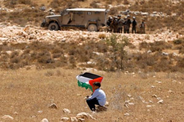 Seorang anak laki-laki memegang bendera Palestina selama demonstrasi menentang penyitaan tanah mereka oleh Israel, di Raba, dekat Jenin, di Tepi Barat yang diduduki Israel, 18 Juli 2025. REUTERS 
