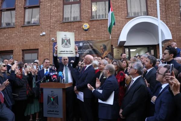 Kepala Misi Palestina di Inggris, Husam Zomlot, bereaksi saat memegang plakat bertuliskan Kedutaan Besar Negara Palestina, dalam upacara pengibaran bendera di luar Misi di London barat pada 22 September 2025.  (FOTO: AFP) 