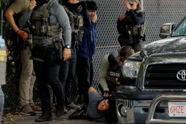 Agen federal, termasuk US Marshals, agen FBI, dan agen HSI, menahan seorang wanita saat putranya bereaksi di sampingnya, dalam penggerebekan penegakan hukum imigrasi di Chelsea, Massachusetts, AS, 26 September 2025. REUTERS 