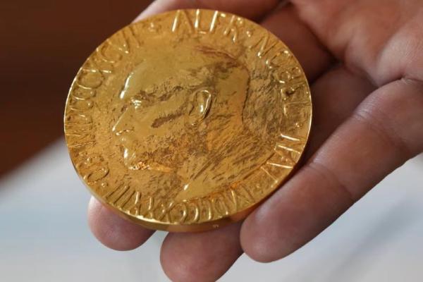 Seorang karyawan Institut Nobel Norwegia memegang replika Medali Nobel Perdamaian di Institut tersebut di Oslo, Norwegia, 9 September 2025. REUTERS 