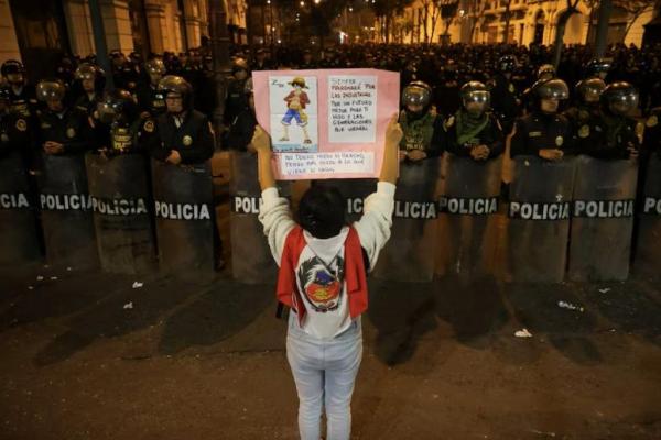Seorang demonstran memegang poster sementara petugas polisi berjaga-jaga selama protes terhadap pemerintahan Presiden Peru, Dina Boluarte, di Lima, Peru, 20 September 2025 
