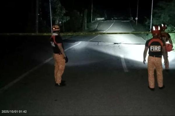 Petugas penyelamat berdiri di depan retakan jalan akibat gempa berkekuatan 6,9 skala Richter di Daanbantayan, Provinsi Cebu, Filipina, 1 Oktober 2025. Handout via REUTERS 