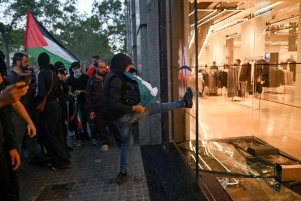 Seorang demonstran menendang kaca jendela toko Zara yang dirusak selama protes pro-Palestina yang mengecam intersepsi pasukan Israel terhadap kapal-kapal Global Sumud Flotilla yang bertujuan mencapai Gaza dan mematahkan blokade laut Israel, di Barcelona, ​​Spanyol, 4 Oktober 2025. REUTERS 