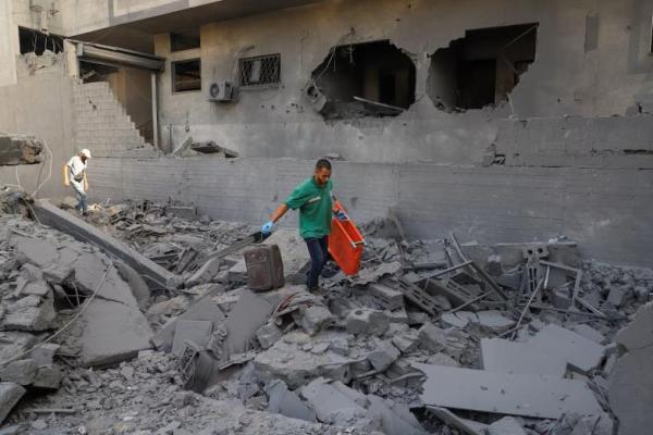Seorang paramedis membawa tandu, sementara warga Palestina memeriksa kerusakan di permukiman setelah operasi Israel di wilayah tersebut di Kota Gaza, 4 Oktober 2025. REUTERS 