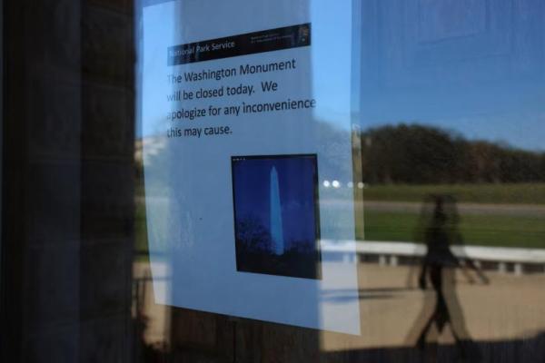 Seseorang berjalan di luar Monumen Washington saat sebuah tanda mengumumkan penutupan, pada hari keempat penutupan sebagian pemerintah di Washington, AS, 4 Oktober 2025. REUTERS 