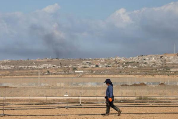 Seorang pria berjalan di sisi Israel di perbatasan Israel-Gaza, sementara asap mengepul dari ledakan di Gaza, terlihat dari Israel selatan, 7 Oktober 2025. REUTERS 
