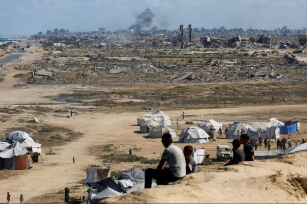 Warga Palestina menyaksikan asap mengepul menyusul ledakan di Kota Gaza, terlihat dari pusat Jalur Gaza, 5 Oktober 2025. REUTERS 