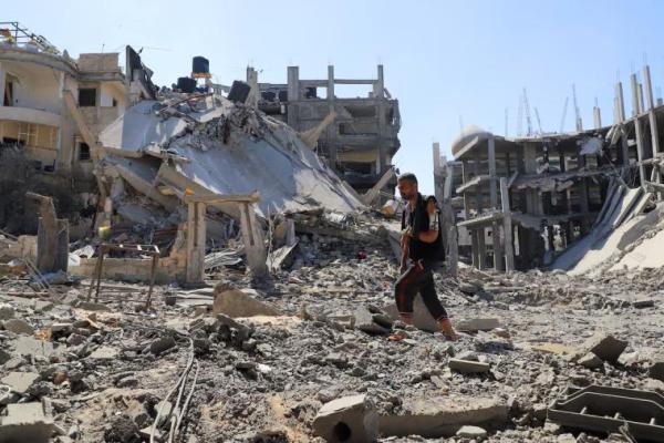 Pria Palestina Jehad Al-Shagnobi, yang terluka dalam serangan Israel sebelumnya di rumahnya, berjalan dengan fiksator eksternal di lengannya untuk memeriksa kerusakan di rumahnya di lingkungan Sabra, setelah operasi Israel, di lingkungan Sabra di Kota Gaza, 8 Oktober 2025. REUTERS 