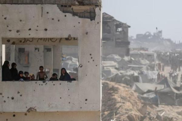 Perempuan dan anak-anak melihat dari sebuah bangunan yang rusak ketika warga Palestina membawa pasokan bantuan yang masuk ke Gaza melalui Israel, di Beit Lahia, Jalur Gaza utara, 2 Agustus 2025. REUTERS 