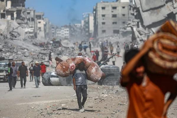 Warga Palestina yang mengungsi di dalam negeri berjalan di antara reruntuhan bangunan yang hancur di tengah gencatan senjata antara Israel dan Hamas, di Kota Gaza. (FOTO: EPA) 