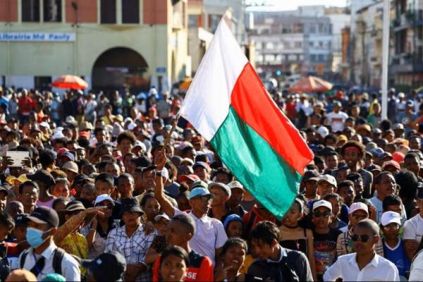 Seorang pengunjuk rasa mengibarkan bendera negaranya saat para demonstran berkumpul di luar balai kota di Independence Avenue dalam protes nasional yang dipimpin pemuda atas seringnya pemadaman listrik dan kekurangan air, di Antananarivo, Madagaskar, 13 Oktober 2025. REUTERS 