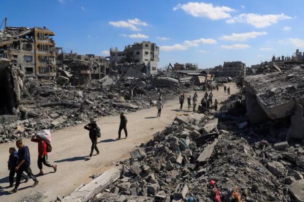 Warga Palestina berjalan melewati reruntuhan bangunan yang hancur, di tengah gencatan senjata antara Israel dan Hamas, di Kota Gaza, 14 Oktober 2025. REUTERS 