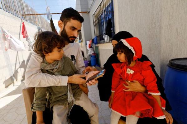 Tahanan Palestina yang dibebaskan, Shadi Abu Sido, duduk bersama istrinya, Hanaa Bahlul, dan anak-anak mereka di rumah mereka di Nuseirat, Jalur Gaza tengah, setelah ia dibebaskan dari tahanan Israel, 14 Oktober 2025. REUTERS 