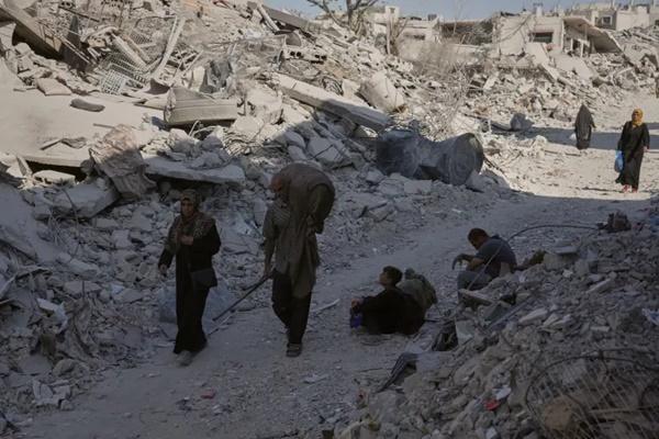 Warga Palestina berjalan di antara bangunan-bangunan yang hancur di Kota Gaza, Kamis, 16 Oktober 2025. (FOTO: AFP) 