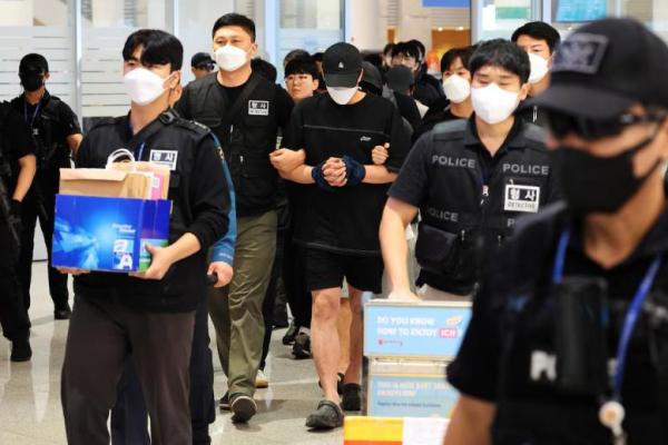 Petugas polisi mengawal warga Korea Selatan yang dideportasi yang diduga terlibat dalam operasi penipuan daring di Kamboja setibanya mereka di Bandara Internasional Incheon di Incheon, Korea Selatan, 18 Oktober 2025. REUTERS 
