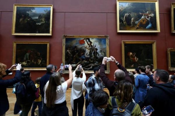 Pengunjung memotret lukisankarya seniman Prancis Eugene Delacroix yang dipajang di sayap salle Mollien Denon di Museum Louvre pada hari pembukaan kembali untuk umum sejak pencurian, di Paris, Prancis, 22 Oktober 2025. REUTERS 