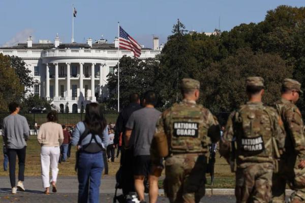 Anggota Garda Nasional dan pengunjung berjalan di dekat Gedung Putih, di Washington, AS, 22 Oktober 2025. REUTERS 