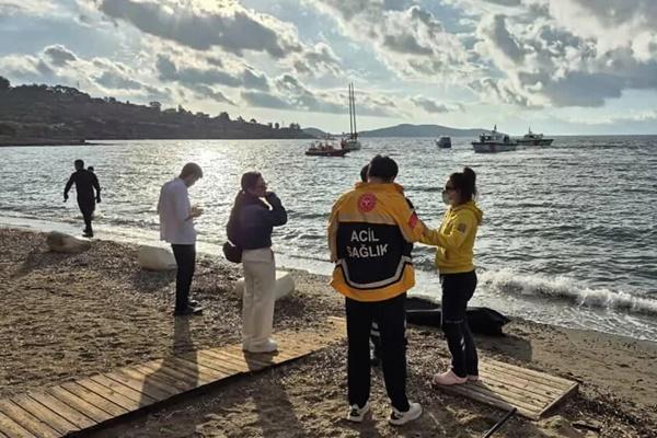 Petugas tanggap darurat Turki berdiri di dekat jenazah yang ditutupi setelah sebuah kapal pengungsi tenggelam di lepas pantai Bodrum, menewaskan sedikitnya 14 orang. (FOTO: AFP) 