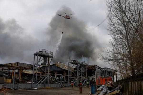 Sebuah helikopter pemadam kebakaran menjatuhkan air di atas gudang makanan yang terkena serangan rudal Rusia, di Kyiv, Ukraina, 25 Oktober 2025. REUTERS 