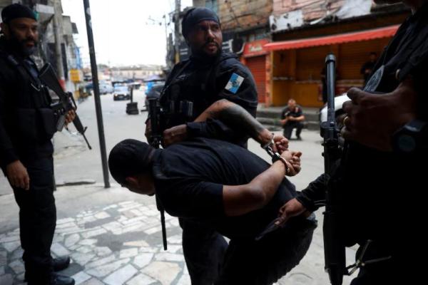 Seorang pria ditahan oleh petugas polisi selama operasi pemberantasan perdagangan narkoba di favela do Penha, Rio de Janeiro, Brasil, 28 Oktober. REUTERS 