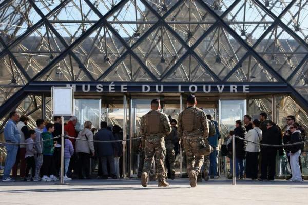 Tentara Prancis dari pasukan keamanan Sentinelle berpatroli melewati Piramida kaca sementara orang-orang mengantre untuk memasuki Museum Louvre, di Paris, Prancis, 30 Oktober 2025. REUTERS 