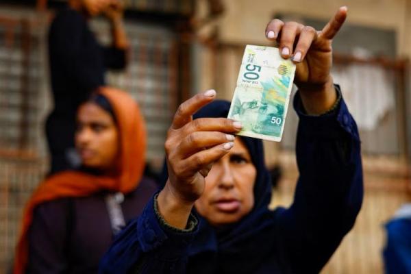 Perempuan Palestina Manal al-Saidi memeriksa uang kertas yang rusak saat ia memperbaiki uang di jalan, di tengah krisis uang tunai, di Nuseirat, Jalur Gaza tengah, 27 Oktober 2025. REUTERS 