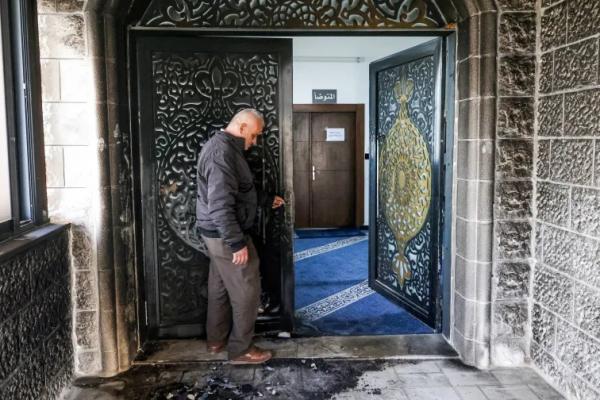 Seorang pria memeriksa pintu masuk Masjid Abu Bakr as-Siddiq yang terbakar di dekat desa Tal, sebelah barat Nablus di Tepi Barat yang diduduki, pada 23 Februari 2026 (Foto: AFP) 