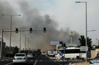 Para pengendara mobil melintas di dekat kepulan asap yang dilaporkan berasal dari serangan Iran di kawasan industri Doha pada 1 Maret 2026 (Foto: AFP)