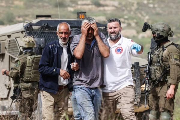 Tentara Israel berjaga-jaga saat petugas medis Palestina membantu seorang pria yang dilaporkan diserang dengan semprotan merica oleh pemukim Yahudi (Foto: AFP) 