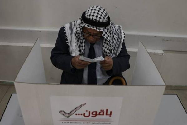 Seorang pria Palestina lanjut usia mengisi surat suara sebelum memberikan suara di tempat pemungutan suara selama pemilihan kota di kota Hebron, Tepi Barat yang diduduki Israel, 25 April 2026. (AFP) 