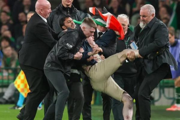 Seorang penyusup lapangan yang membawa bendera Palestina dikeluarkan saat pertandingan sepak bola UEFA Nations League antara Republik Irlandia dan Austria (Foto: Paul Faith/AFP) 