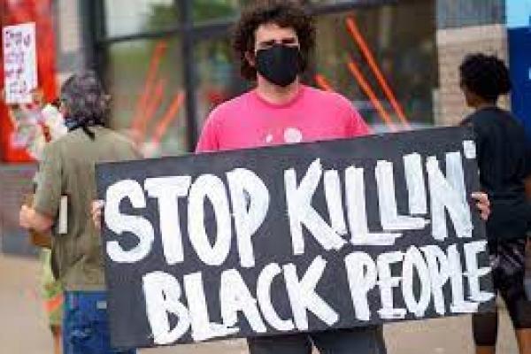 Seorang lelaki memegang plakat Stop Killing Black People ketika memprotes di dekat daerah tempat seorang petugas Kepolisian Minneapolis yang diduga membunuh George Floyd, pada 26 Mei 2020 di Minneapolis, Minnesota, Amerika Serikat.(foto: AFP/kompas.com) 
