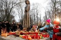 Anak-anak meletakkan bulir gandum saat mereka mengunjungi monumen korban Holodomor di Kyiv, Ukraina 28 November 2020. Foto: Reuters