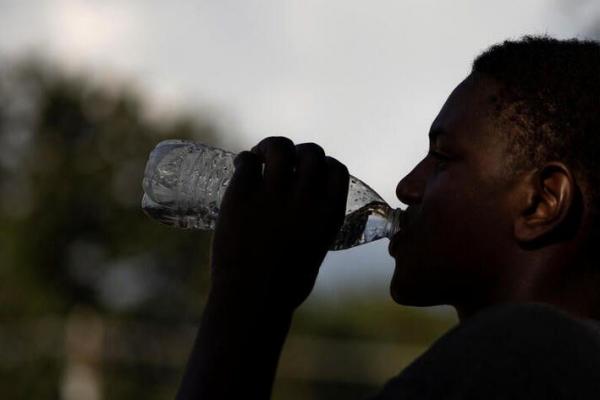 Seorang sukarelawan minum air saat istirahat di lokasi distribusi air kemasan di Jackson, Mississippi, AS, 2 September 2022. Foto: Reuters 