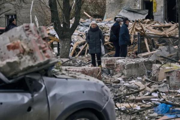 Orang-orang berdiri di depan bangunan yang rusak berat setelah serangan Rusia di Sloviansk, wilayah Donetsk, Ukraina (FOTO: Libkos/AP Photo) 