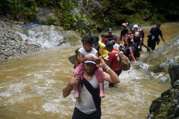 Seorang migran membawa seorang anak saat mereka bersama orang lain melanjutkan perjalanan ke perbatasan AS, di Acandi, Kolombia 9 Juli 2023. Foto: Reuters 
