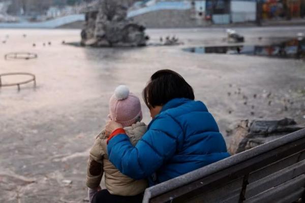 Seorang wanita dan seorang anak duduk di sebuah taman di Beijing, Tiongkok 12 Januari 2024. Foto: Reuters 