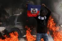 Seorang demonstran mengibarkan bendera Haiti selama protes terhadap pemerintahan Perdana Menteri Ariel Henry, di Port-au-Prince, Haiti 1 Maret 2024. Foto: REUTERS